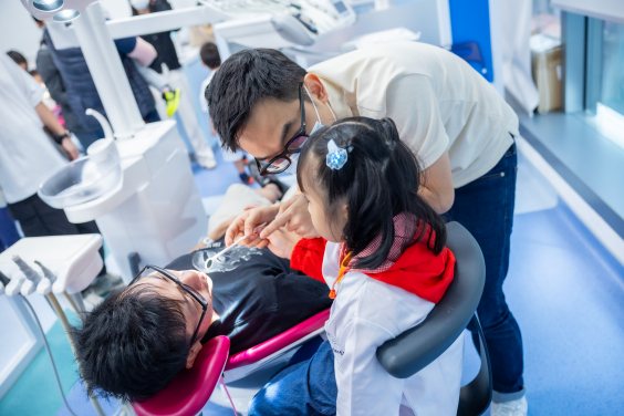 A mini-dentist conducts dental check-up on his parent under the supervision of a resident dentist.
 