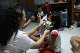 在曼谷其中一個研究家庭中，護士正教導小孩如何正確佩戴口罩。